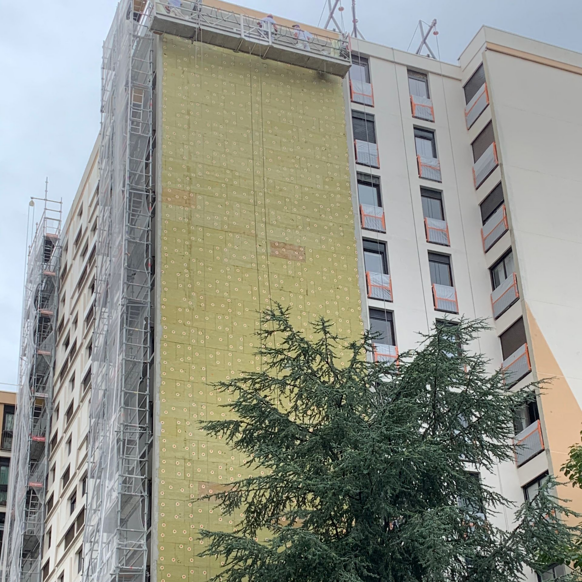 Bâtiment en construction avec échafaudage et panneaux isolants.