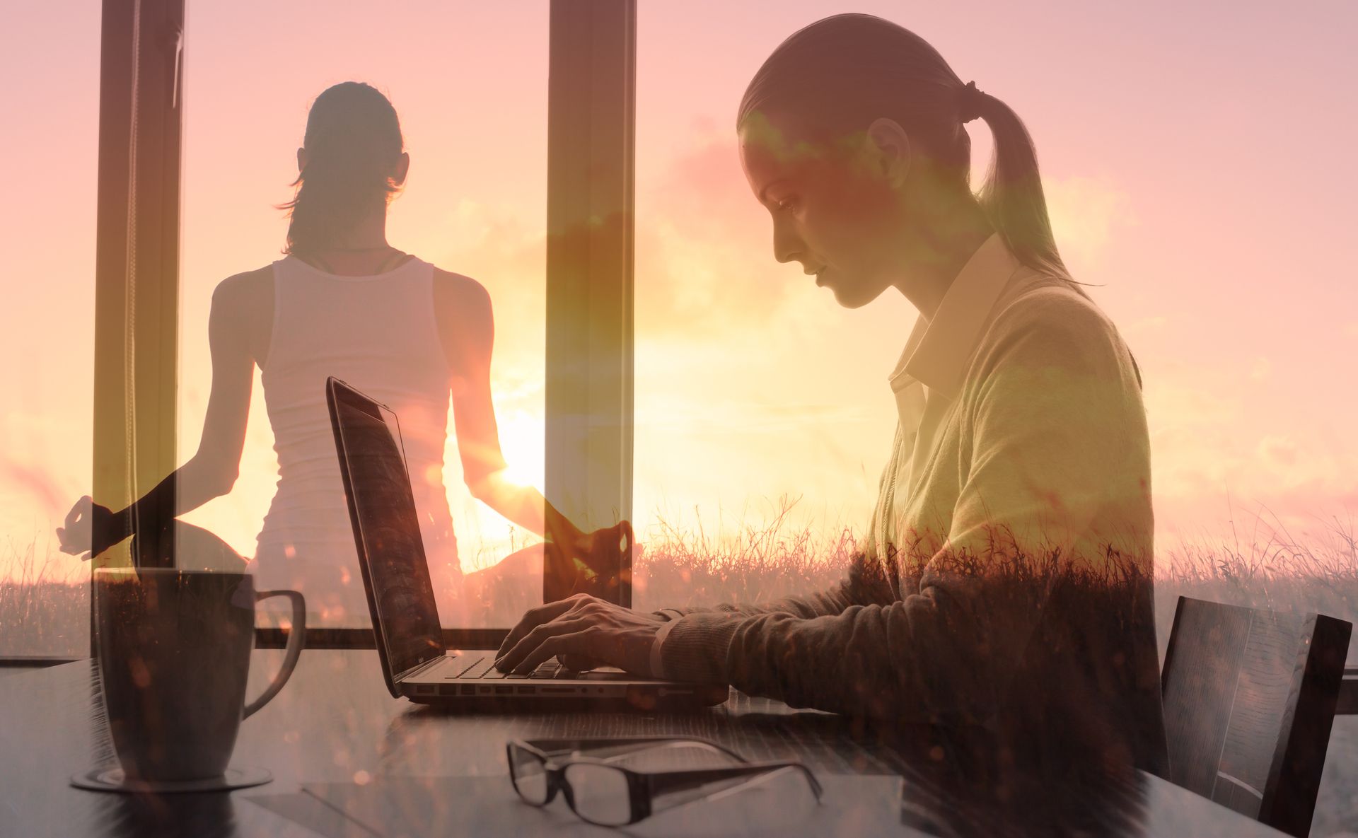 Femme travaillant sur un ordinateur portable, vue du lever du soleil, avec la silhouette d'une personne méditant en arrière-plan.