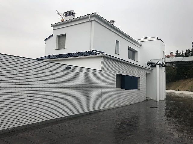 Una casa blanca con techo azul y una pared de ladrillo
