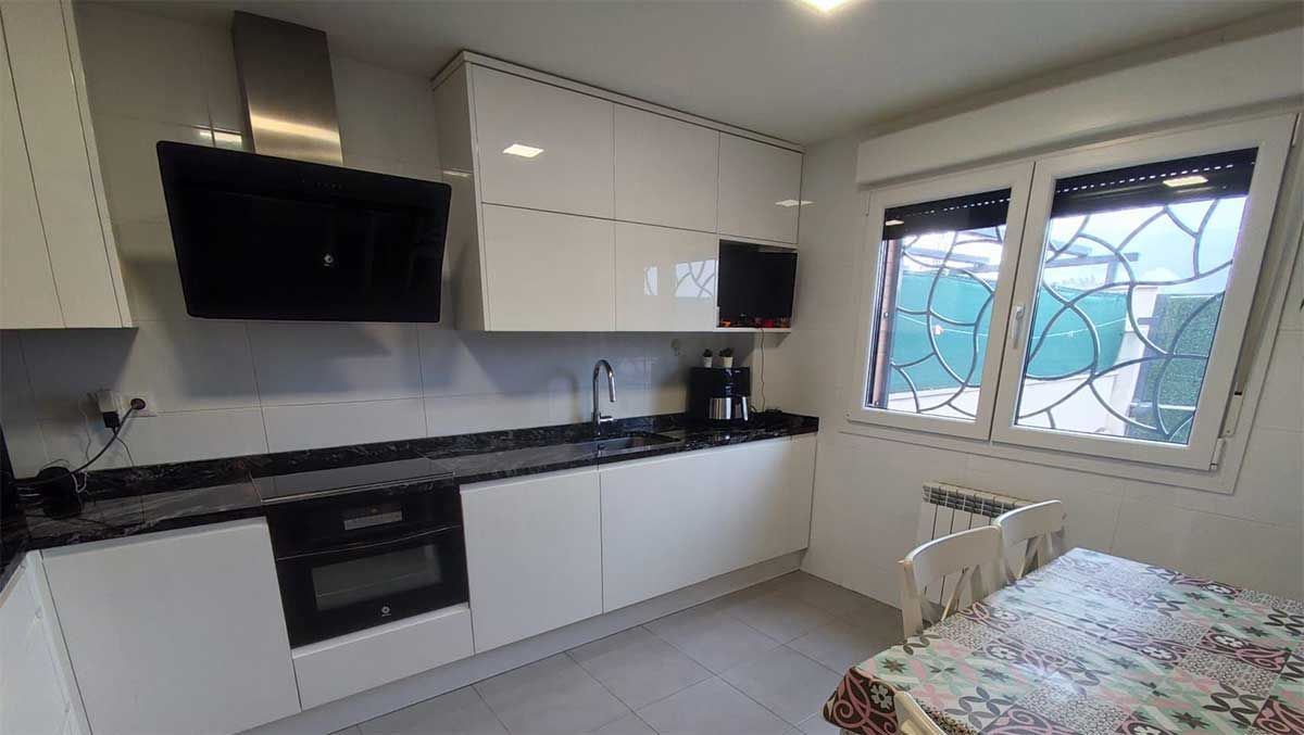 Patio trasero con terraza, suelo de hormigón gris, casa, zona de estar techada.