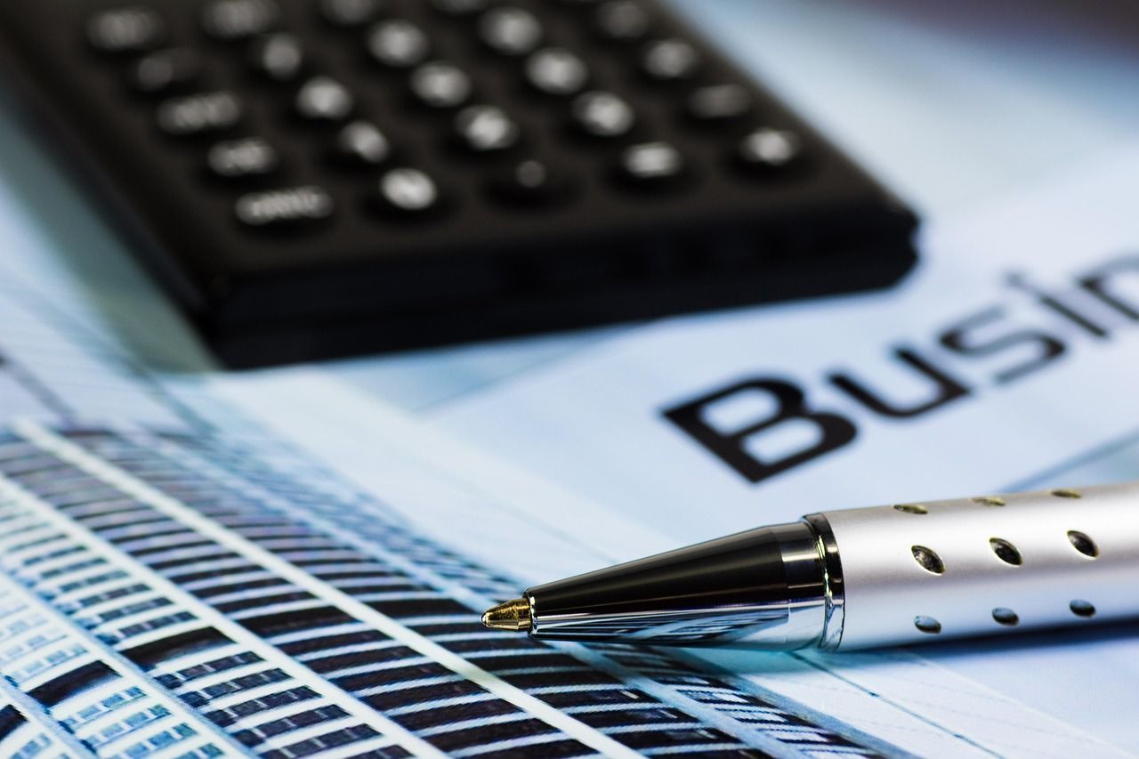 Silver pen on business document next to a calculator.
