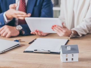 Agentes inmobiliarios revisando documentos con modelo de casa.