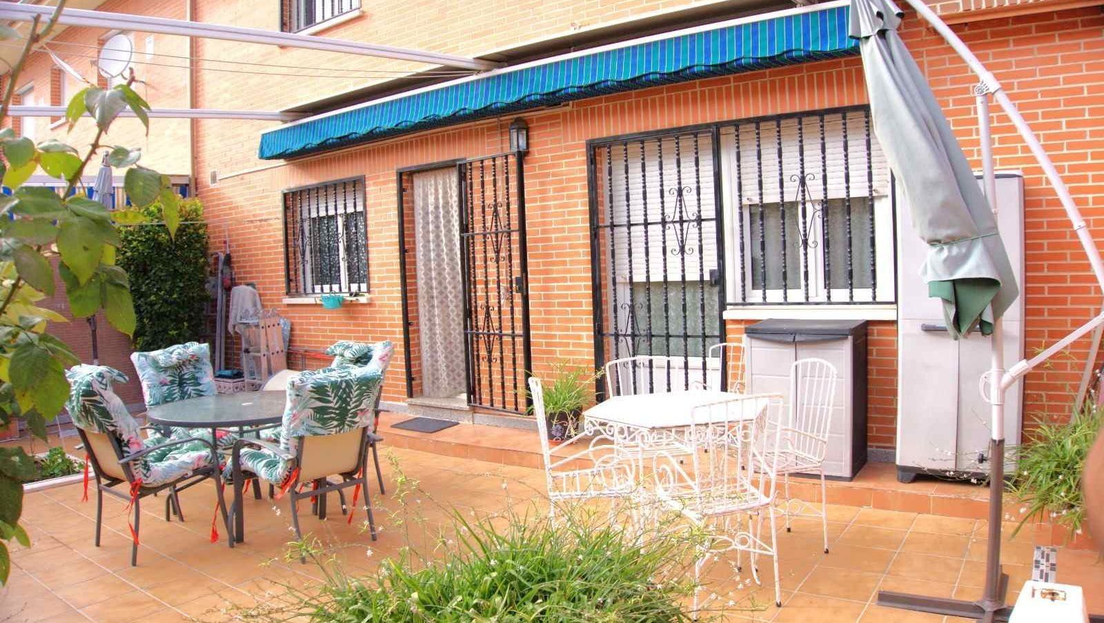 Un patio con una mesa y sillas frente a un edificio de ladrillo.