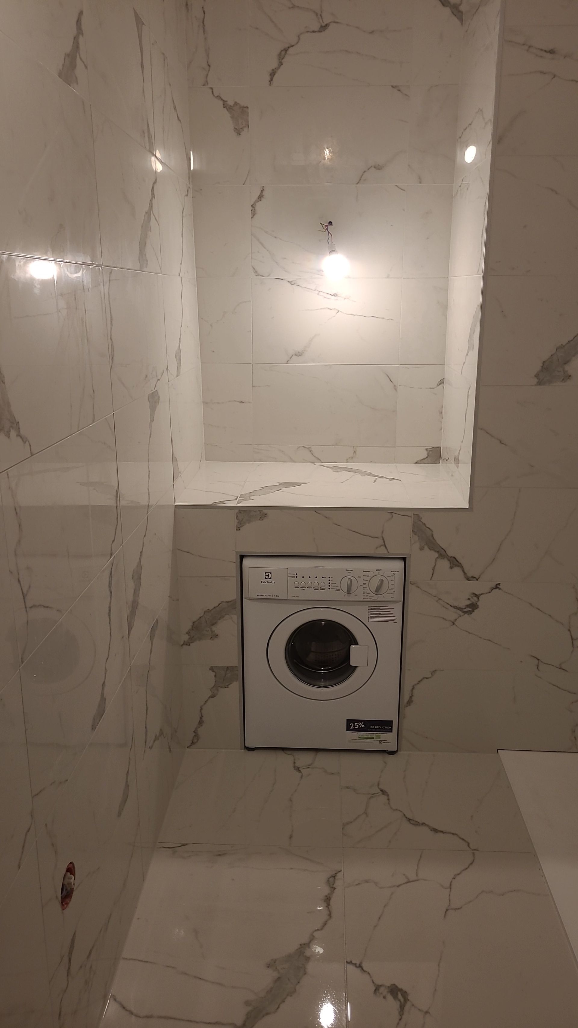 Salle de bains en marbre avec lave-linge intégré.