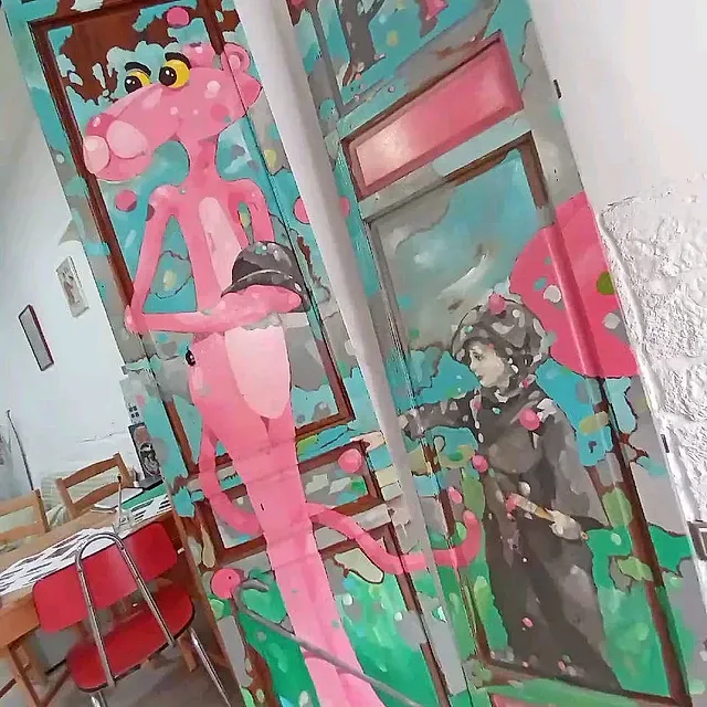 Una pantera rosa está pintada en el costado de una puerta.
