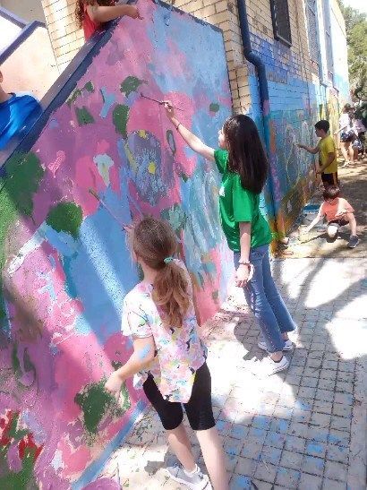Un grupo de niños está pintando un mural en una pared.