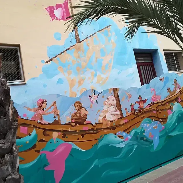 Un mural en el costado de un edificio muestra un barco en el océano.