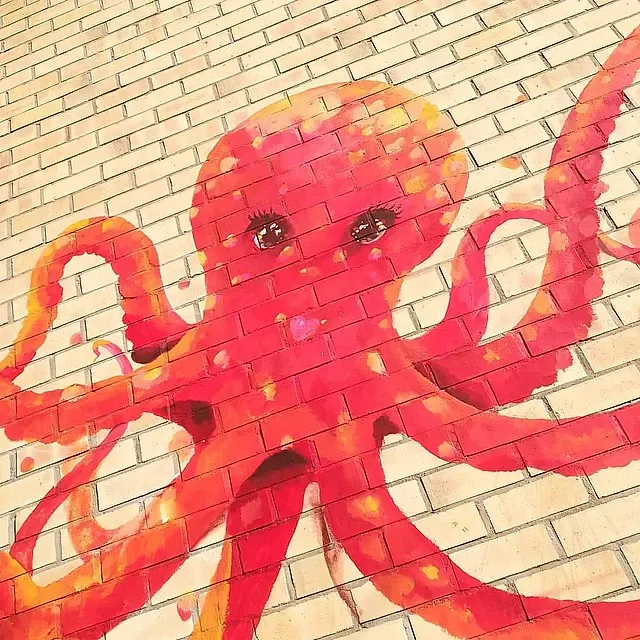 Un pulpo rojo está pintado en una pared de ladrillos.