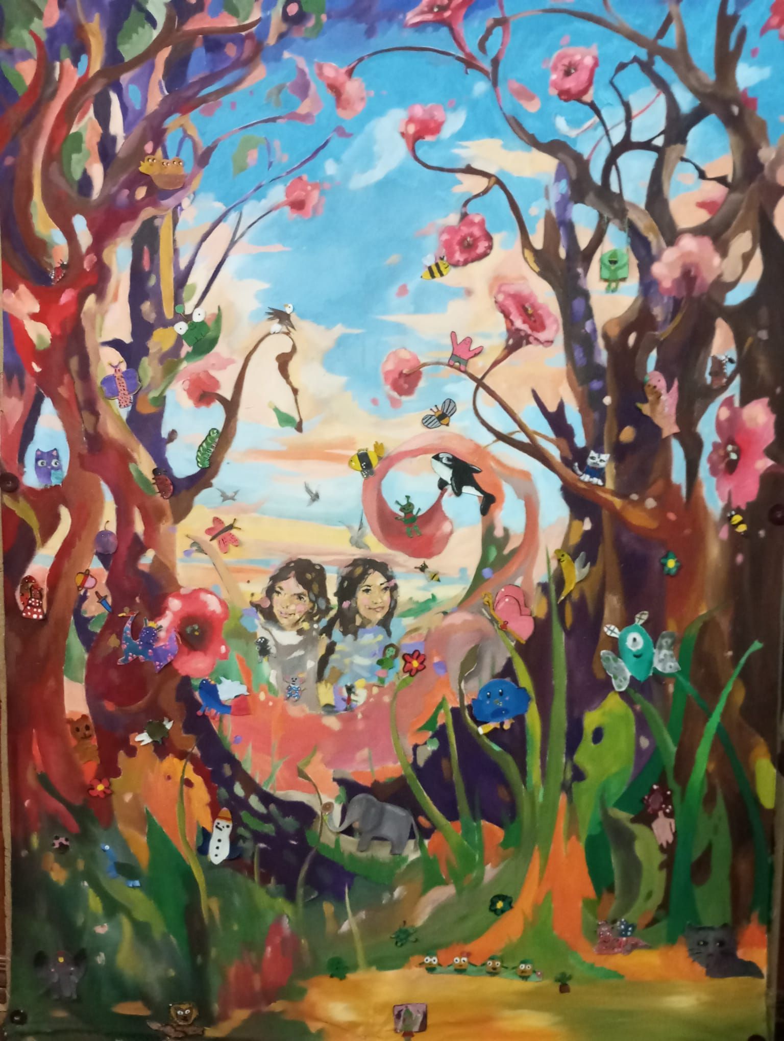 Cuadro caprichoso que representa a dos niños en un bosque lleno de flores, con pájaros y un cielo azul brillante.