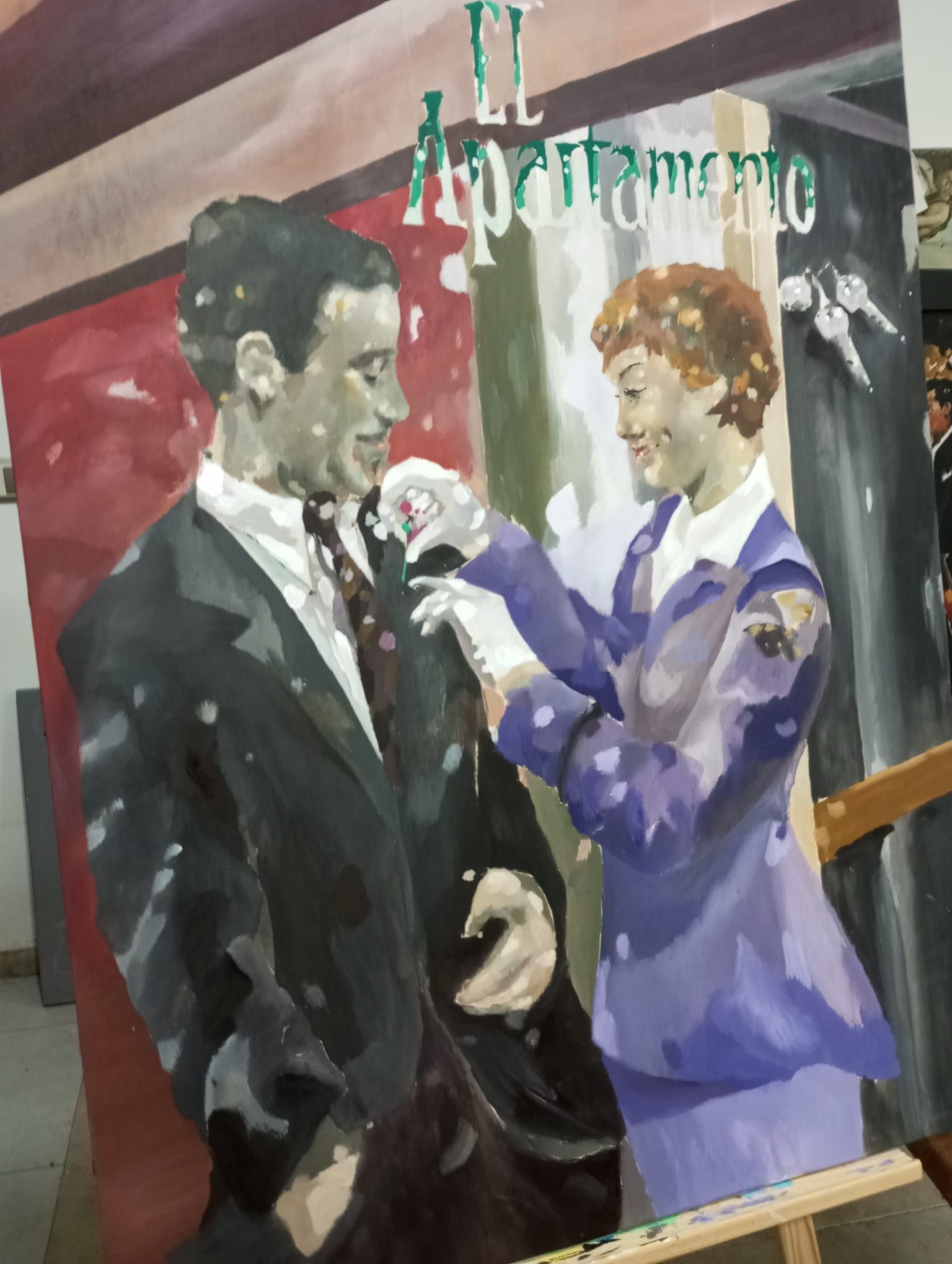 Un hombre y una mujer con ropa formal bailan en un mural pintado con tonos rojos, morados y verdes.