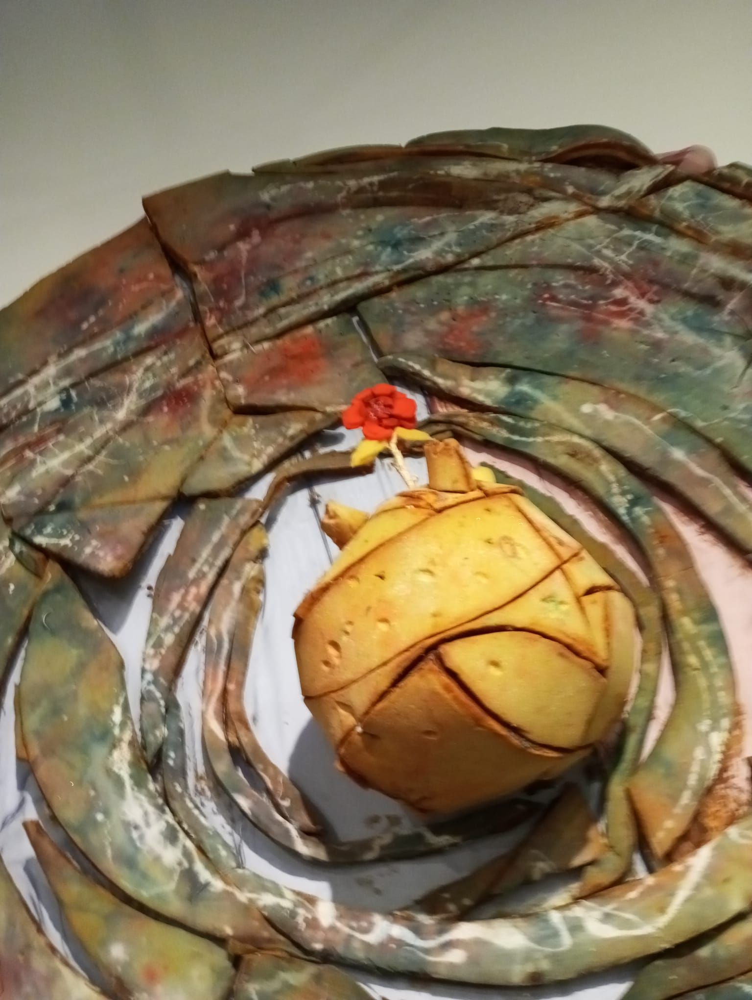 Una fruta amarilla envuelta en capas de hojas o papel, colocada en el centro de una cesta circular tejida.