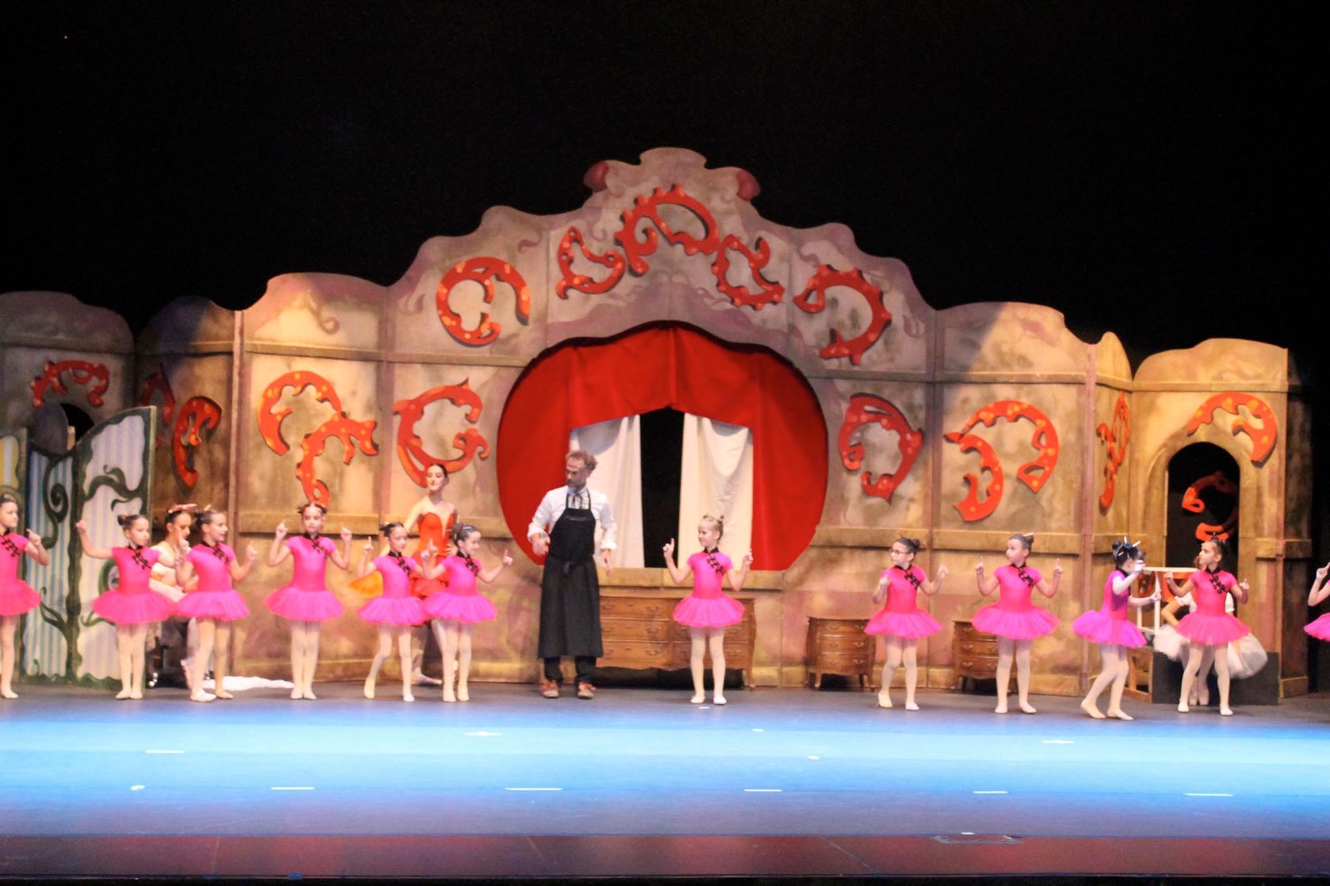 Un grupo de chicas jóvenes con tutús rosas están bailando en un escenario.