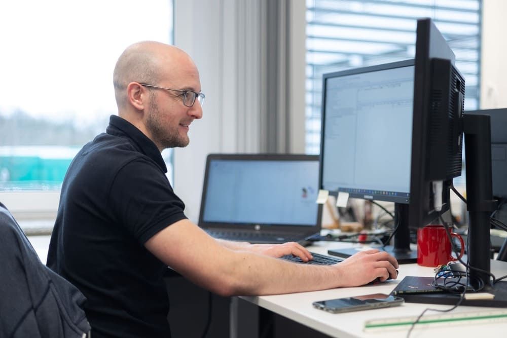 Ein Mann sitzt an einem Schreibtisch vor einem Computer.