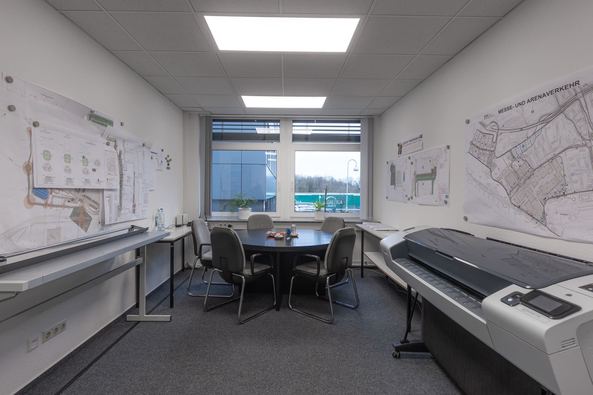 Ein Konferenzraum mit Tisch, Stühlen und einem Drucker.