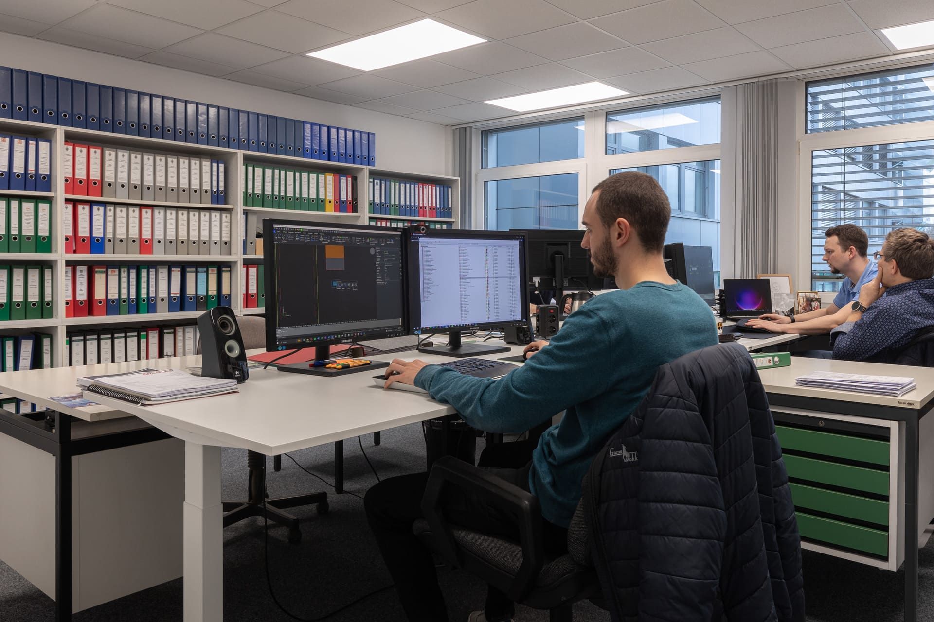 Ein Mann sitzt in einem Büro an einem Schreibtisch und arbeitet am Computer.