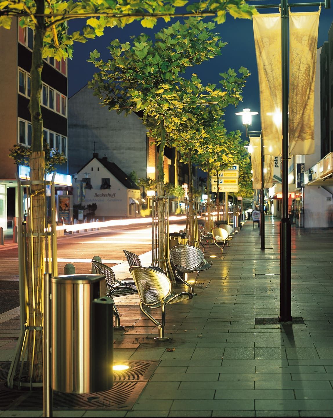 Eine Reihe von Bänken auf einem Bürgersteig in der Nacht