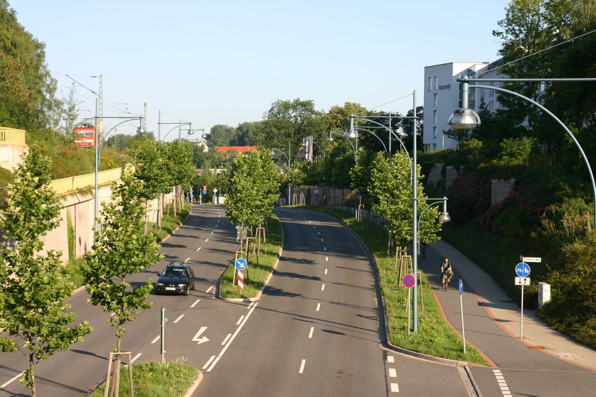 Ein Auto fährt eine Straße entlang, die auf beiden Seiten von Bäumen bewachsen ist