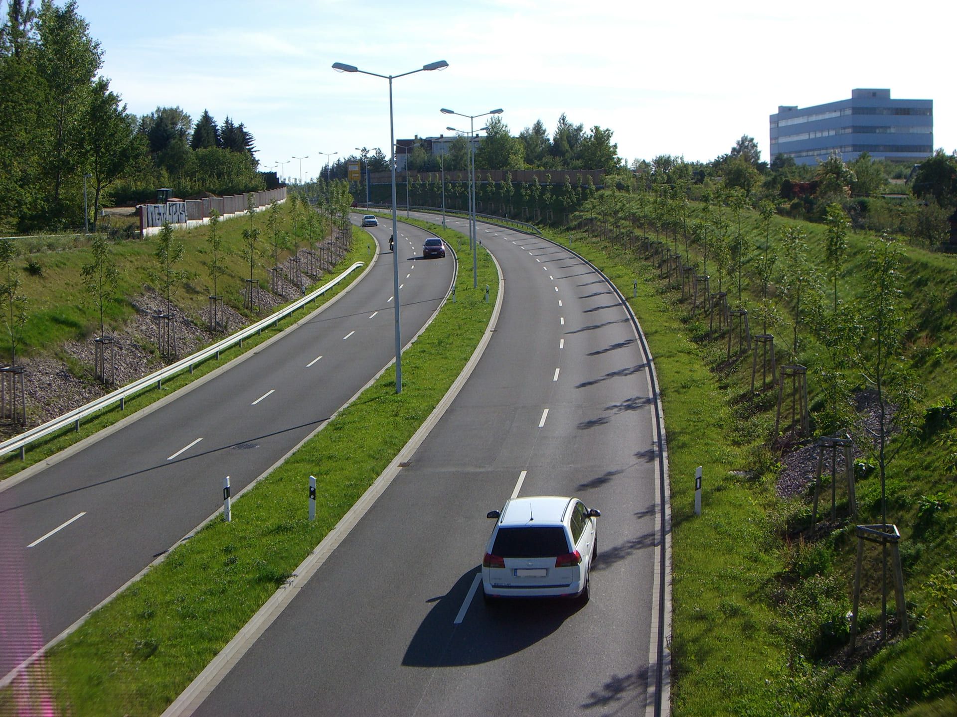 Ein weißes Auto fährt eine kurvenreiche Autobahn entlang