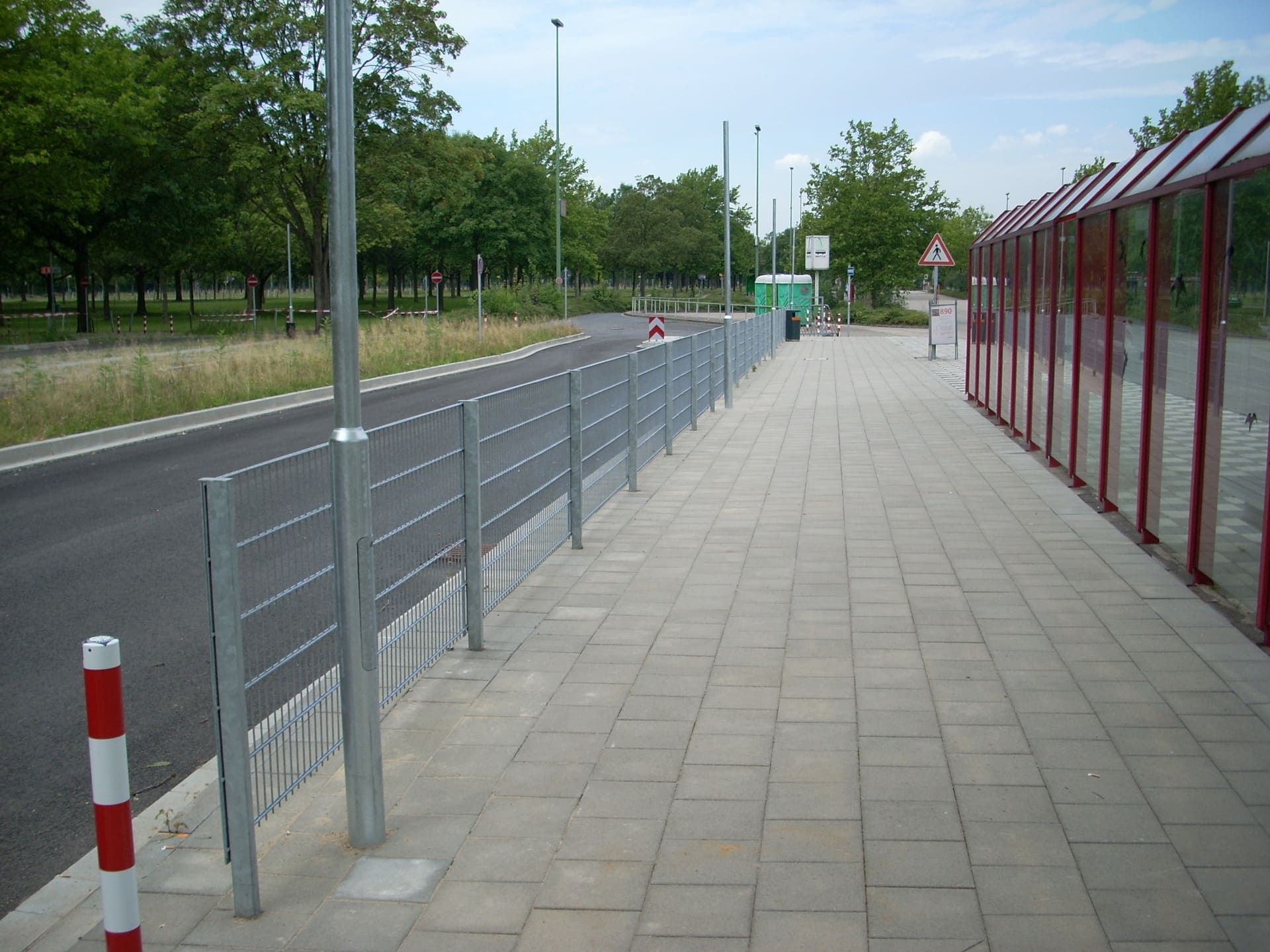Ein Zaun am Straßenrand mit Bäumen im Hintergrund