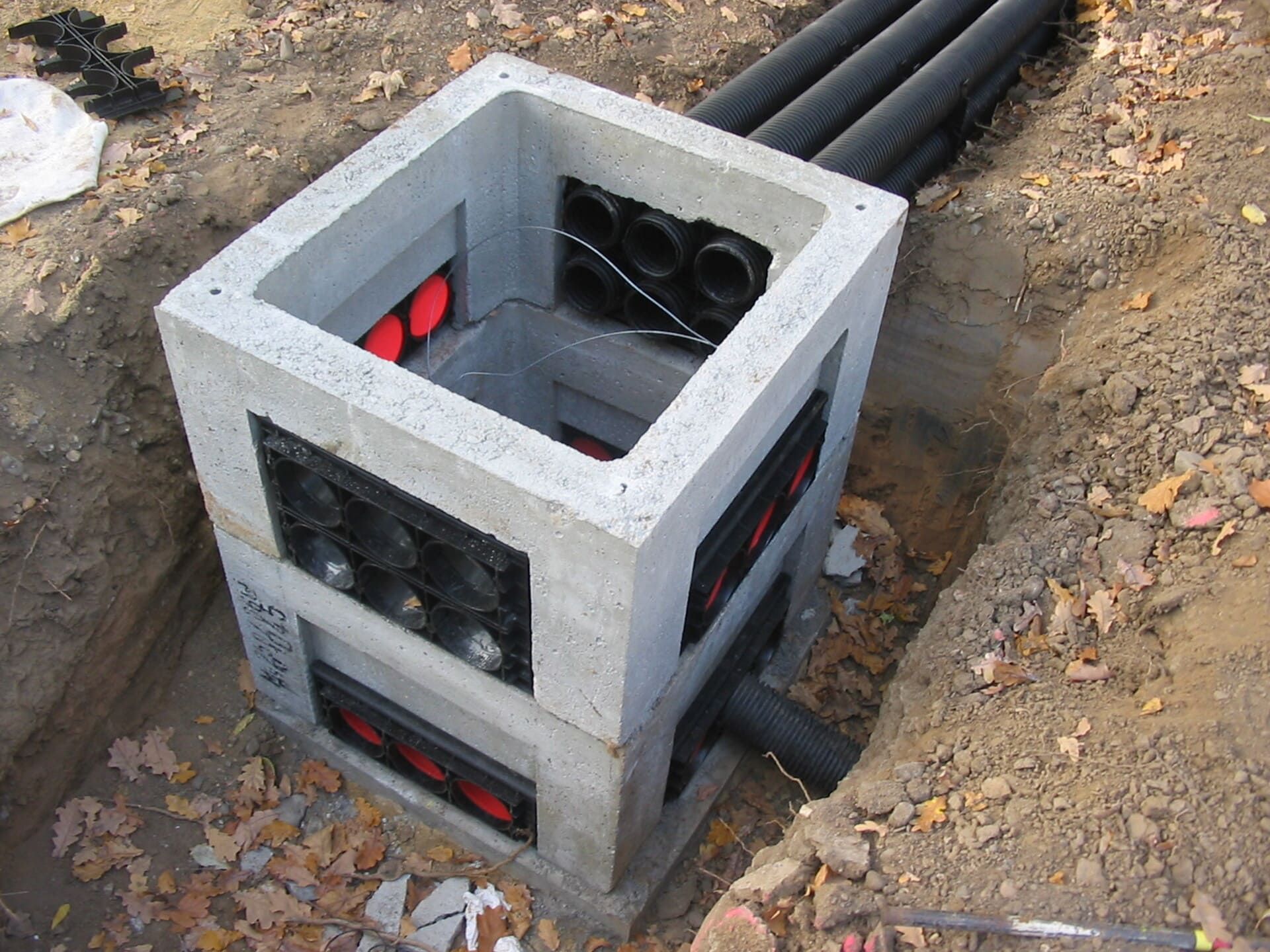 Ein Betonkasten steht im Dreck neben einigen Rohren