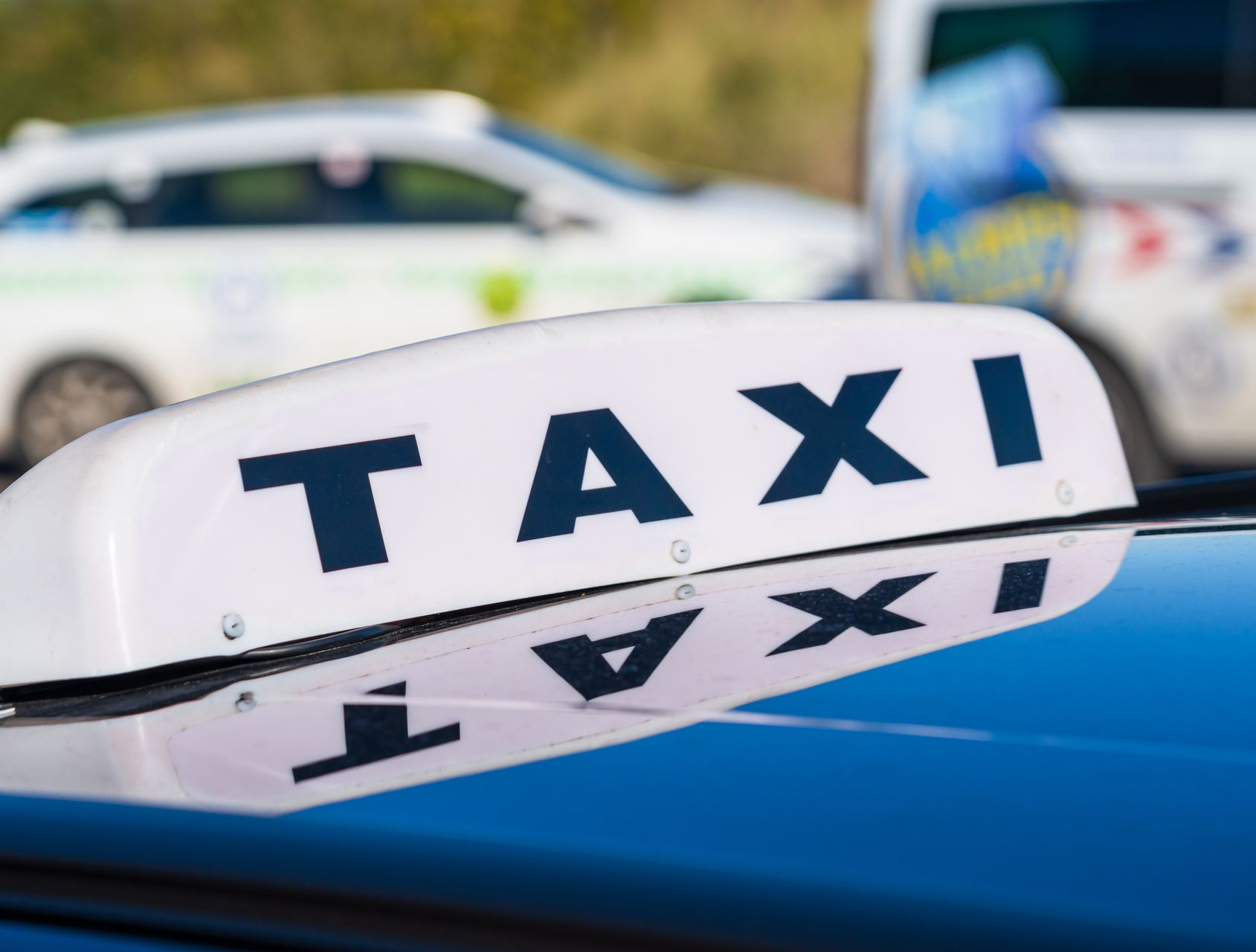 Panneau de taxi sur le toit d'une voiture, avec un véhicule flou.