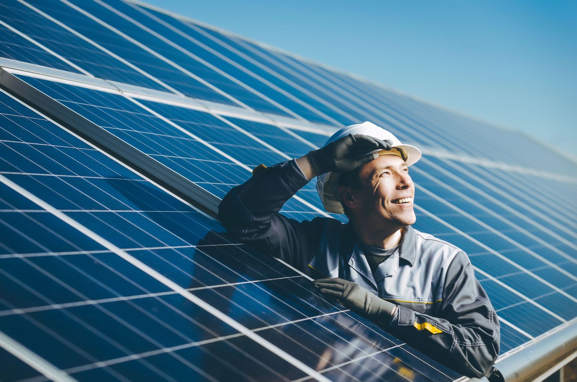 Homme portant un casque fort entre des panneaux photovoltaïques