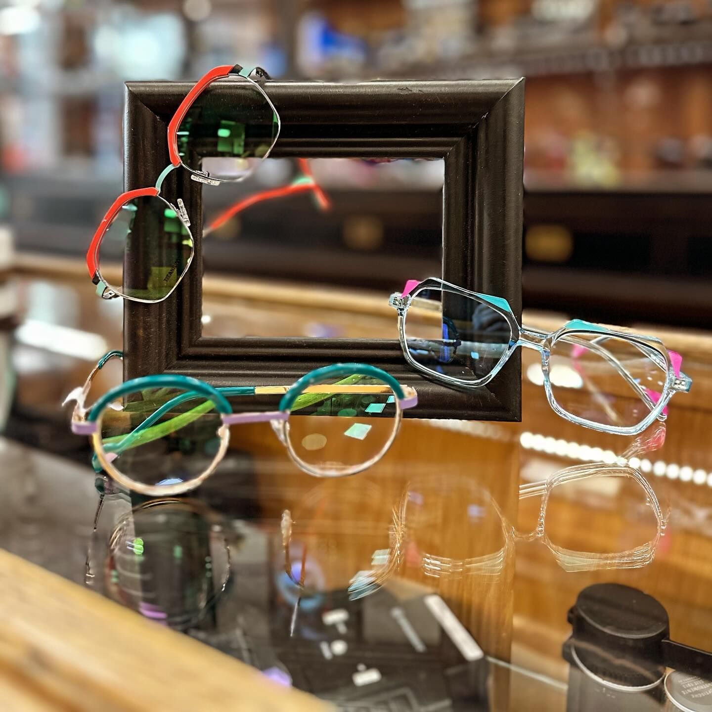 Des lunettes aux montures colorées disposées sur une vitrine.