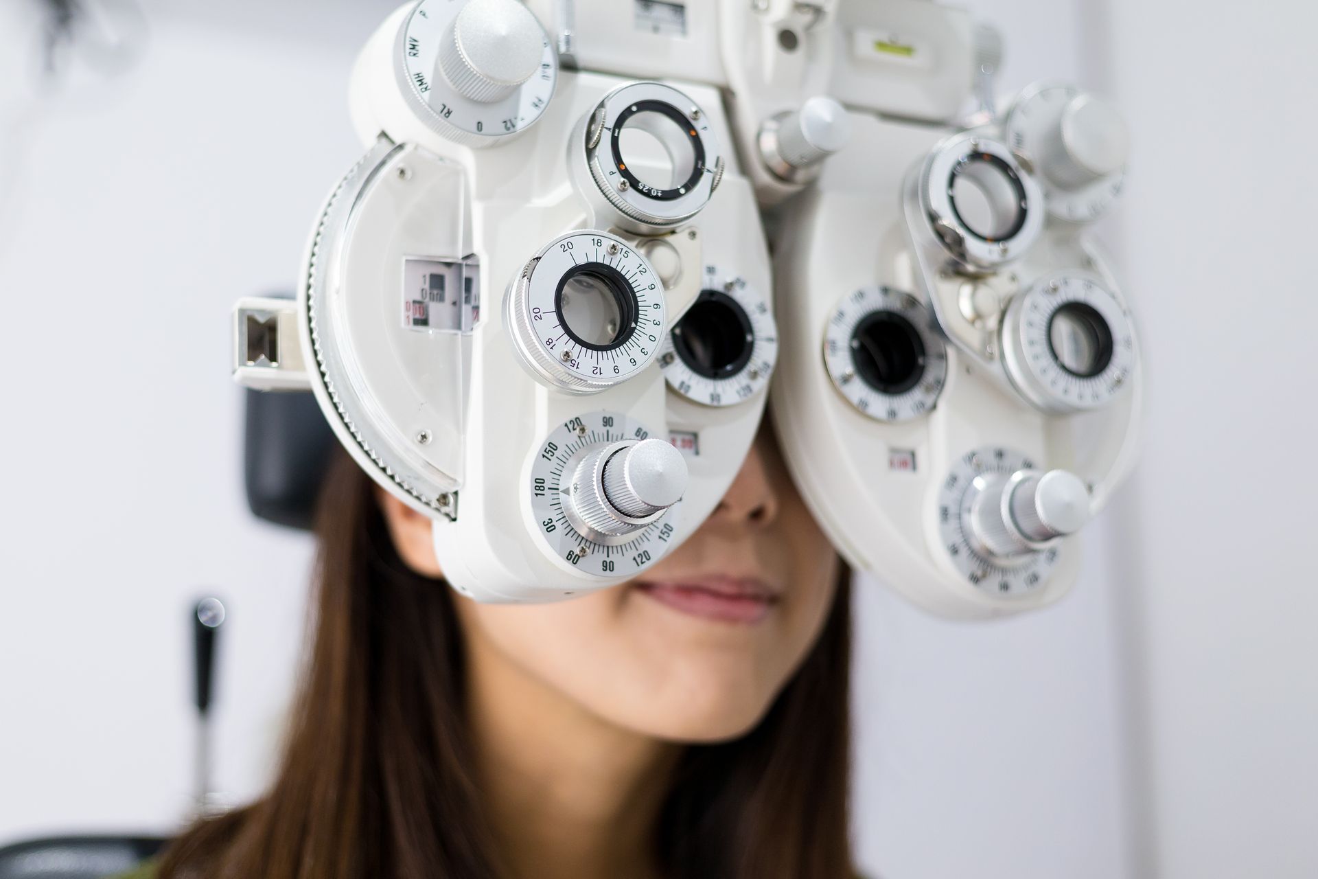 Une personne regarde à travers un appareil d'examen de la vue chez un opticien.