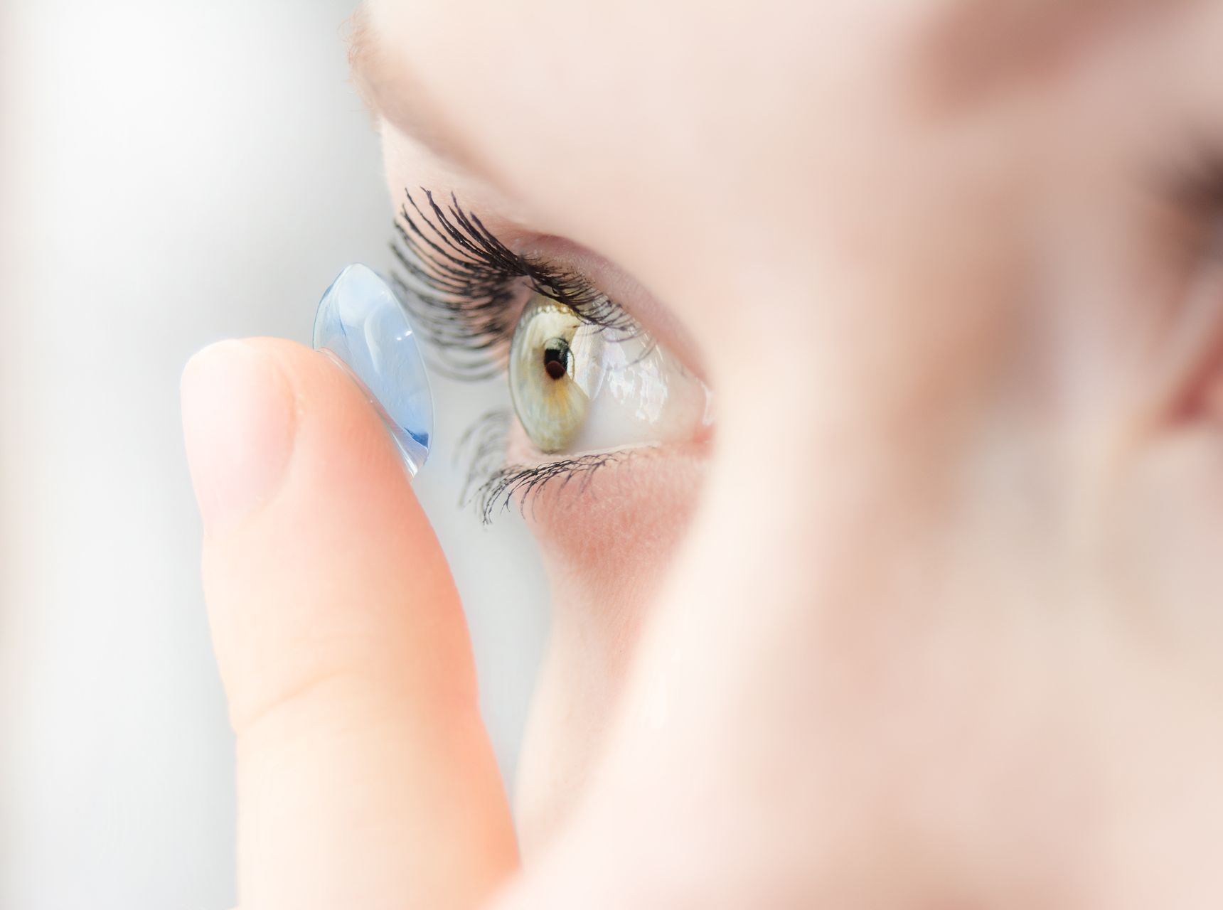 Personne insérant une lentille de contact dans son œil.