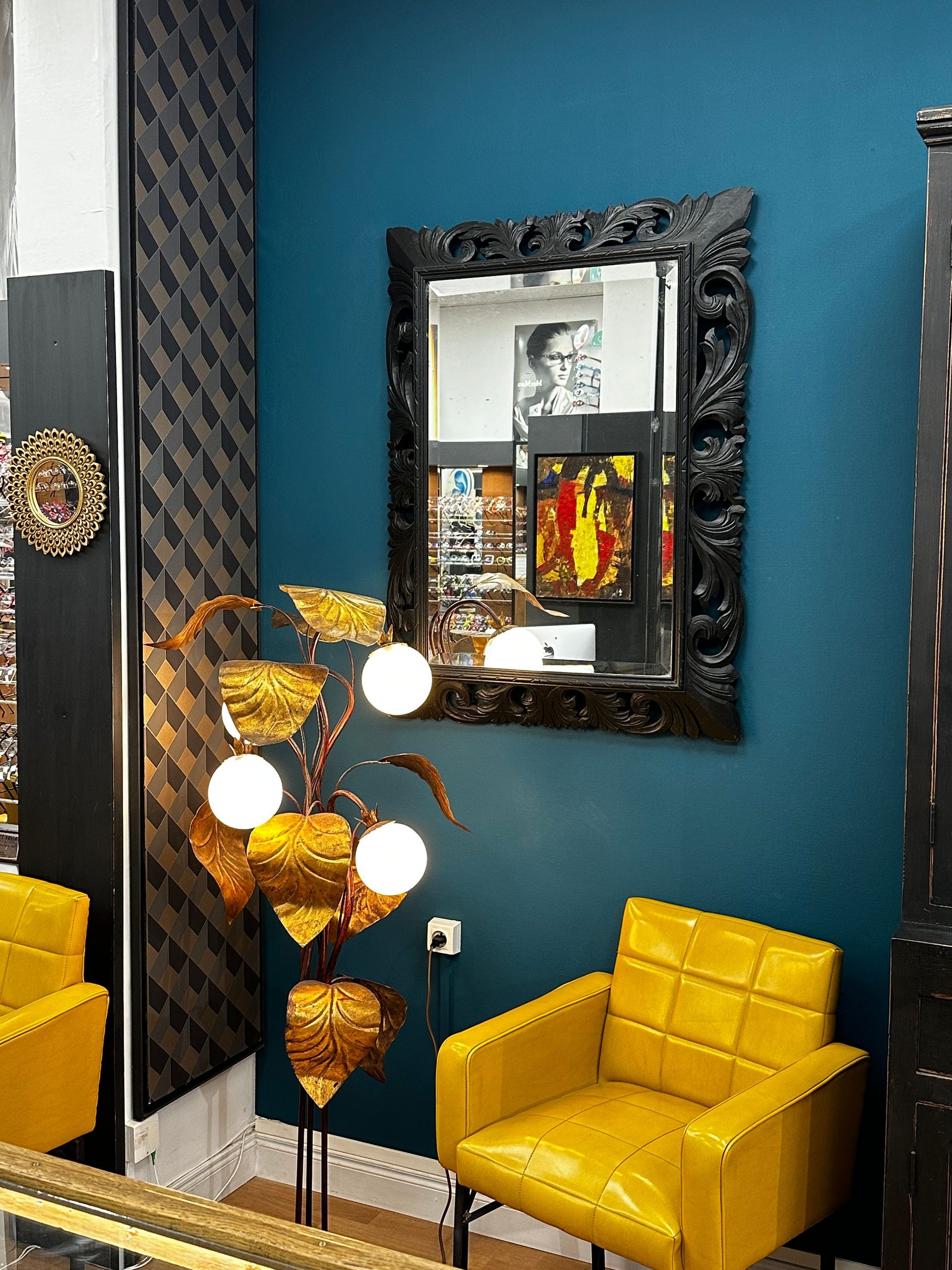 Fauteuil, luminaire et miroir reflétant des affiches publicitaires de lunettes.