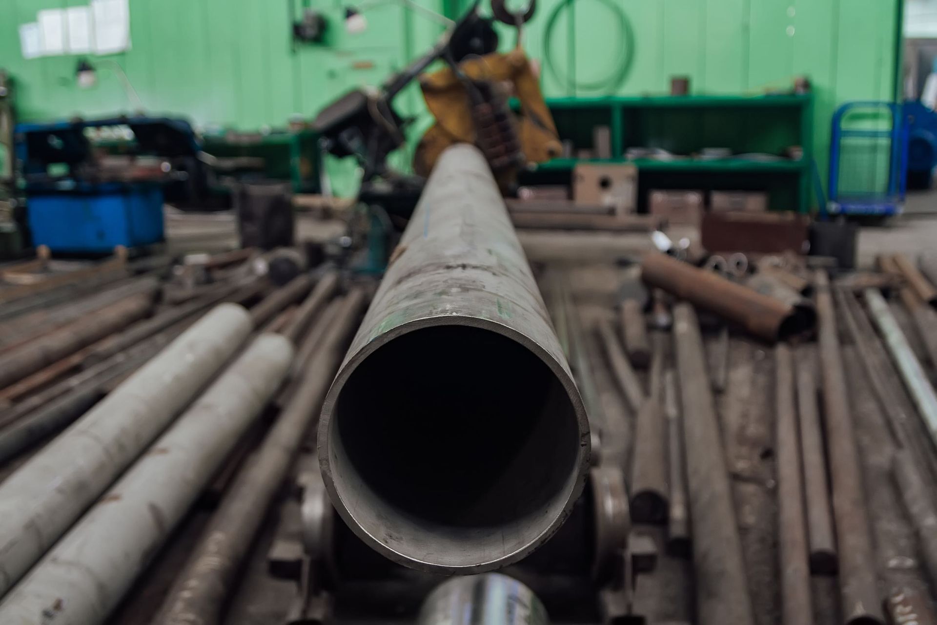 Un gran tubo de metal se encuentra encima de una pila de tubos de metal en una fábrica.