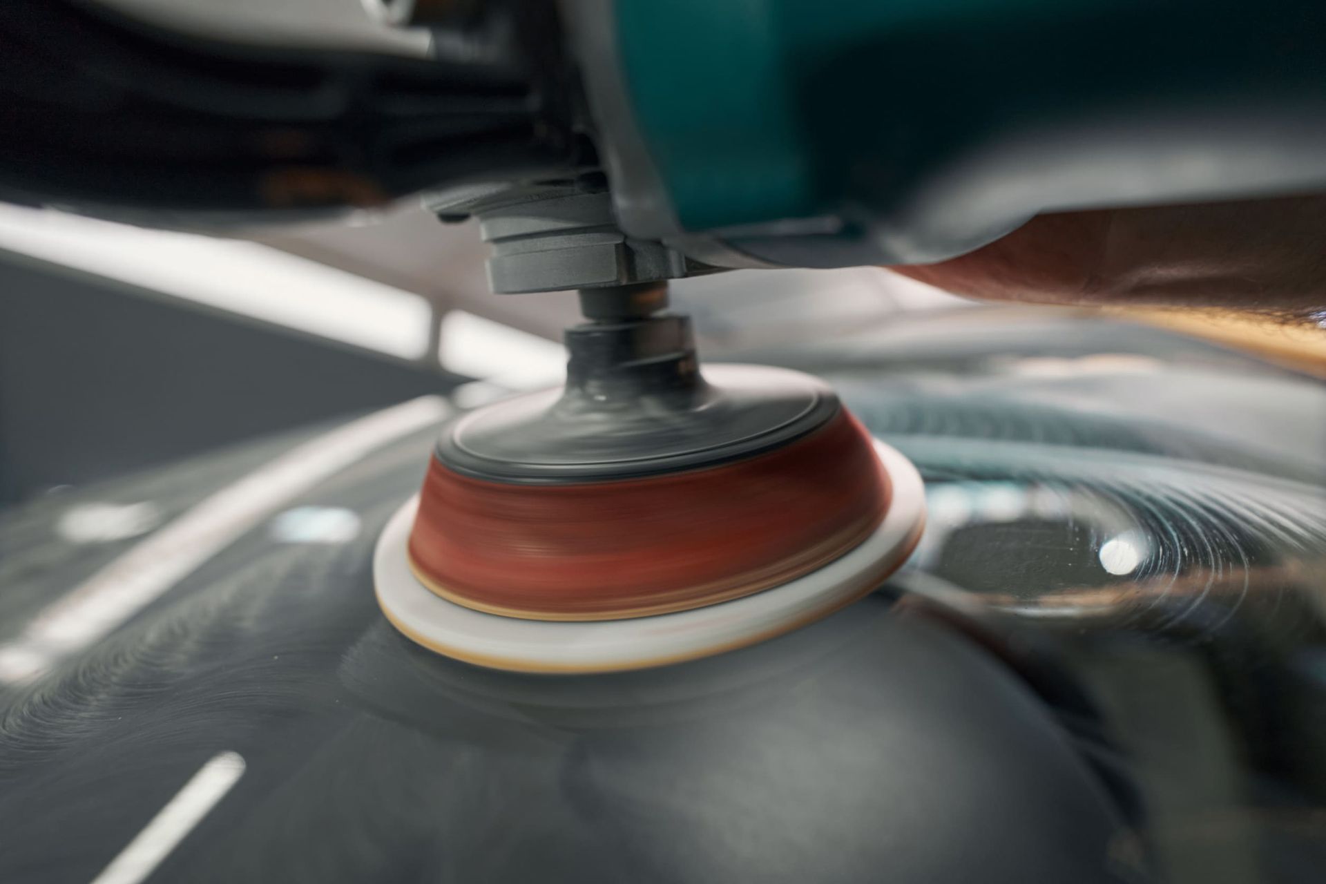 Un primer plano de una persona puliendo un coche con una máquina.