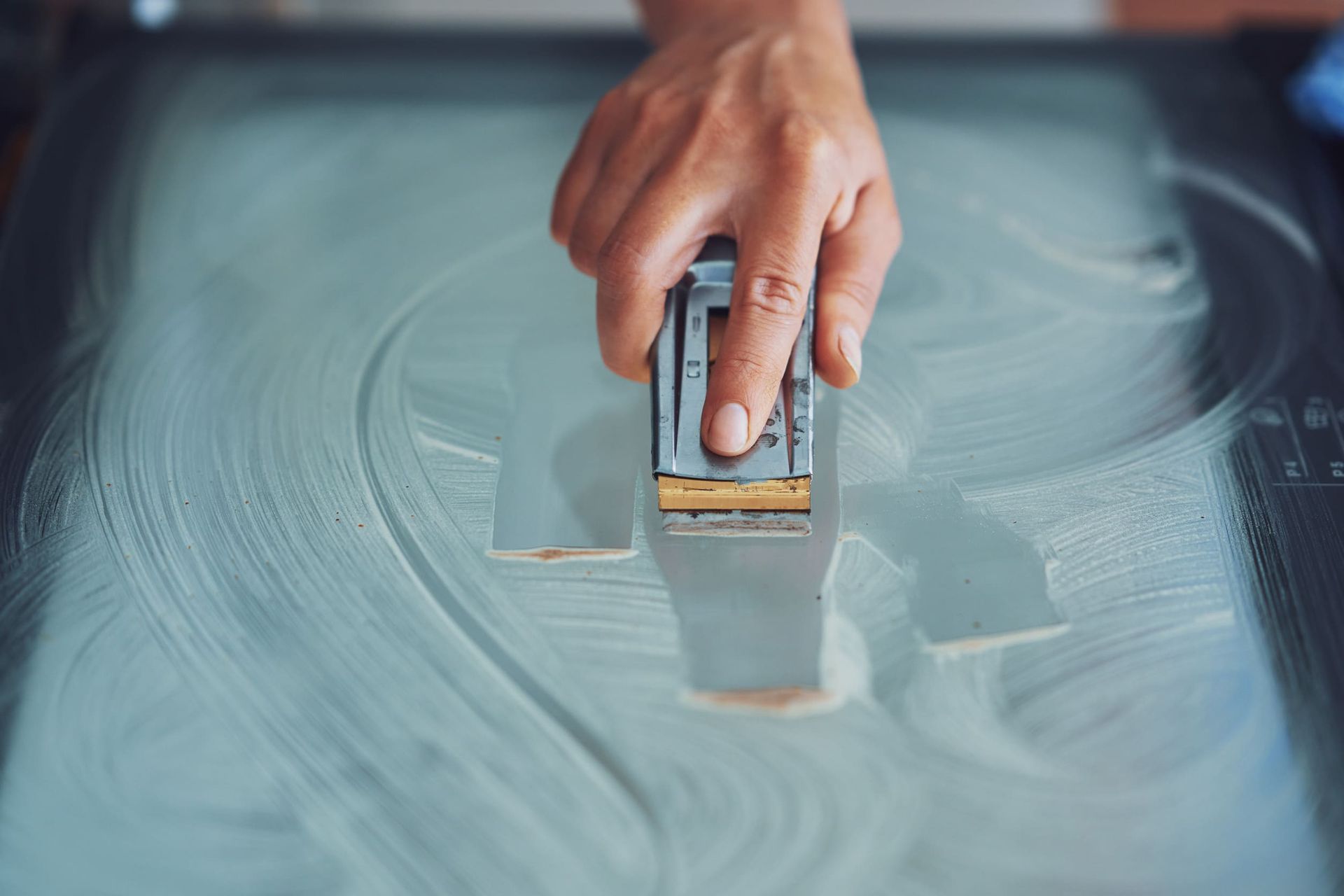 Una persona está limpiando una puerta de vidrio con un raspador.