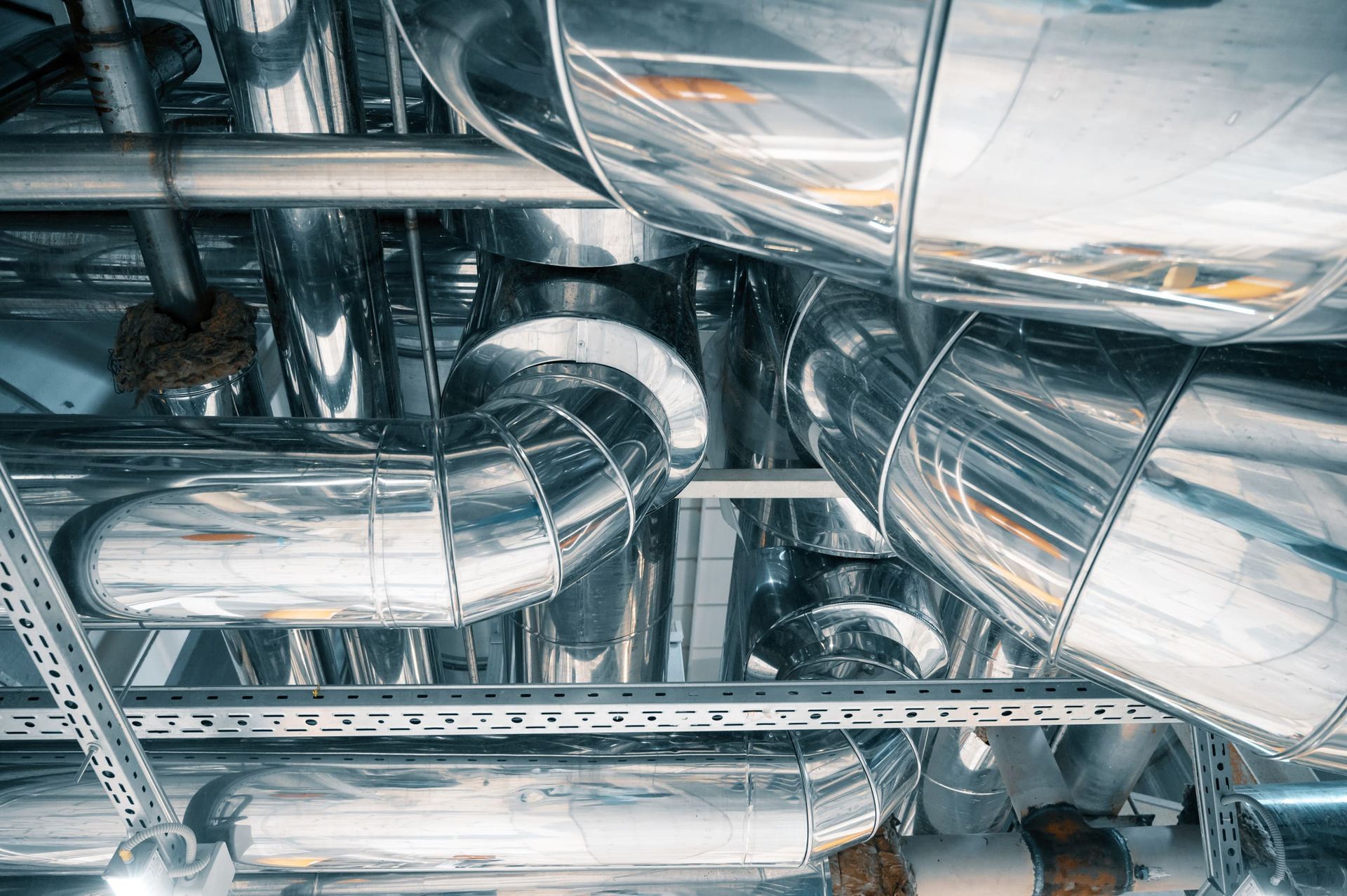 Un montón de tubos de metal cuelgan del techo de un edificio.