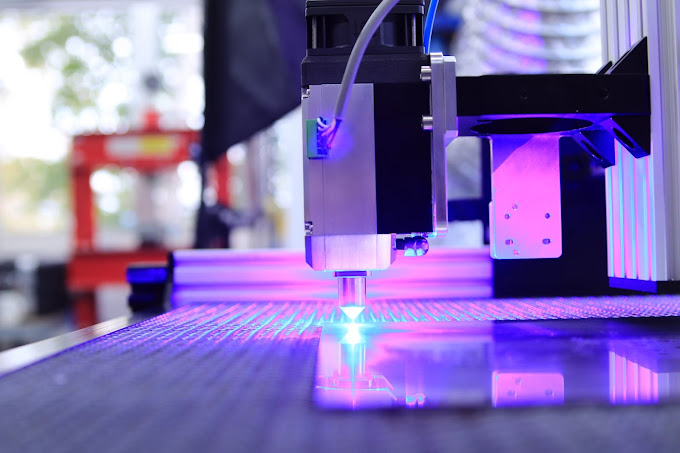 Una máquina está cortando un trozo de vidrio con una luz violeta.