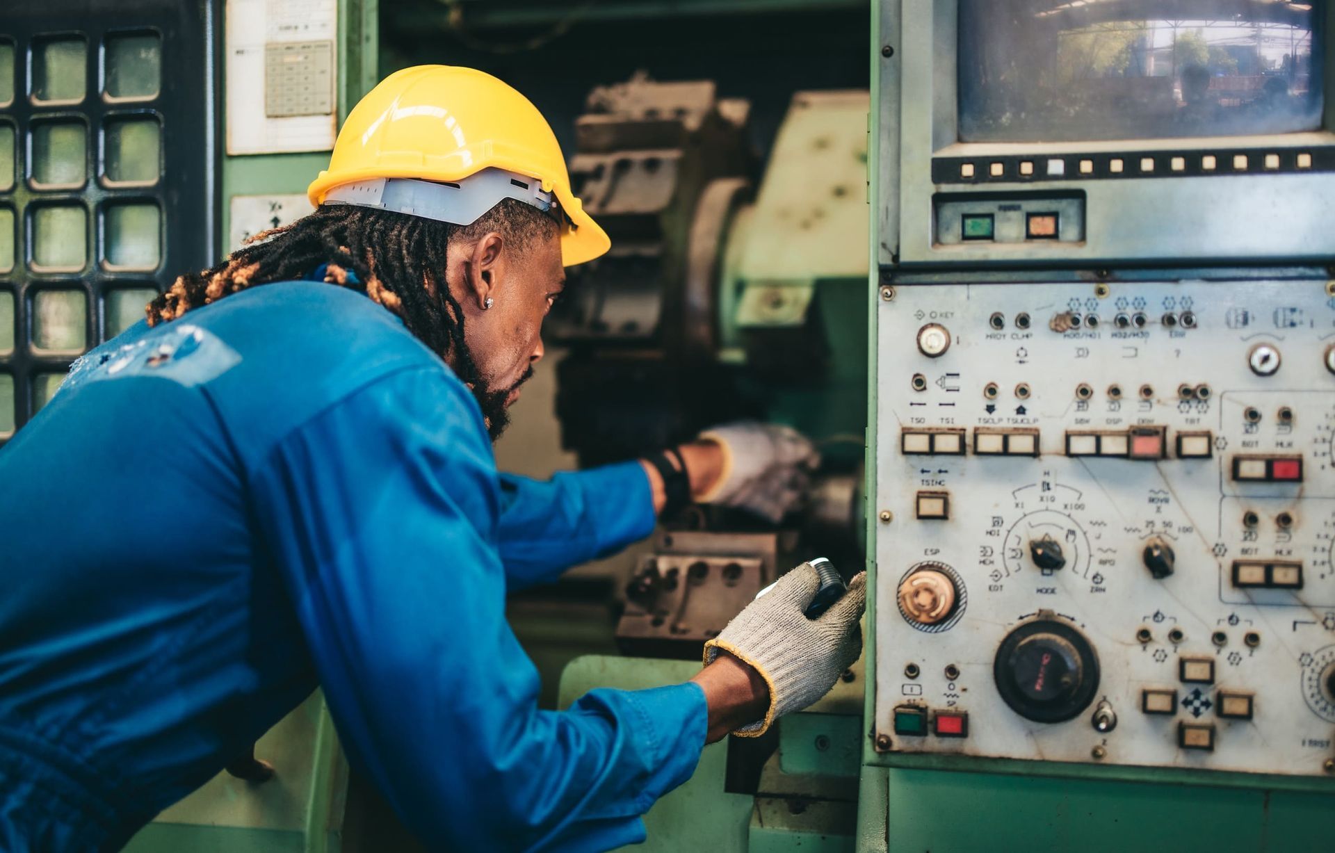 Un hombre que lleva un casco está trabajando en una máquina en una fábrica.