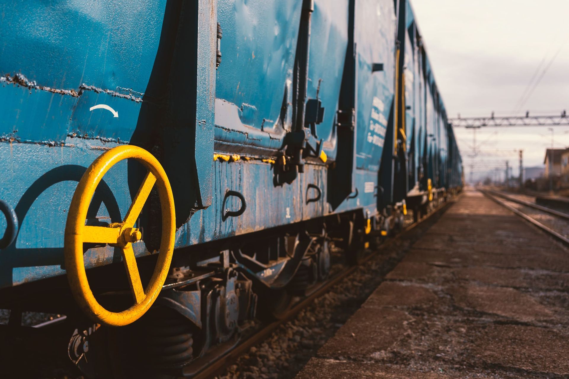 Un tren azul con una rueda amarilla al costado está en las vías.