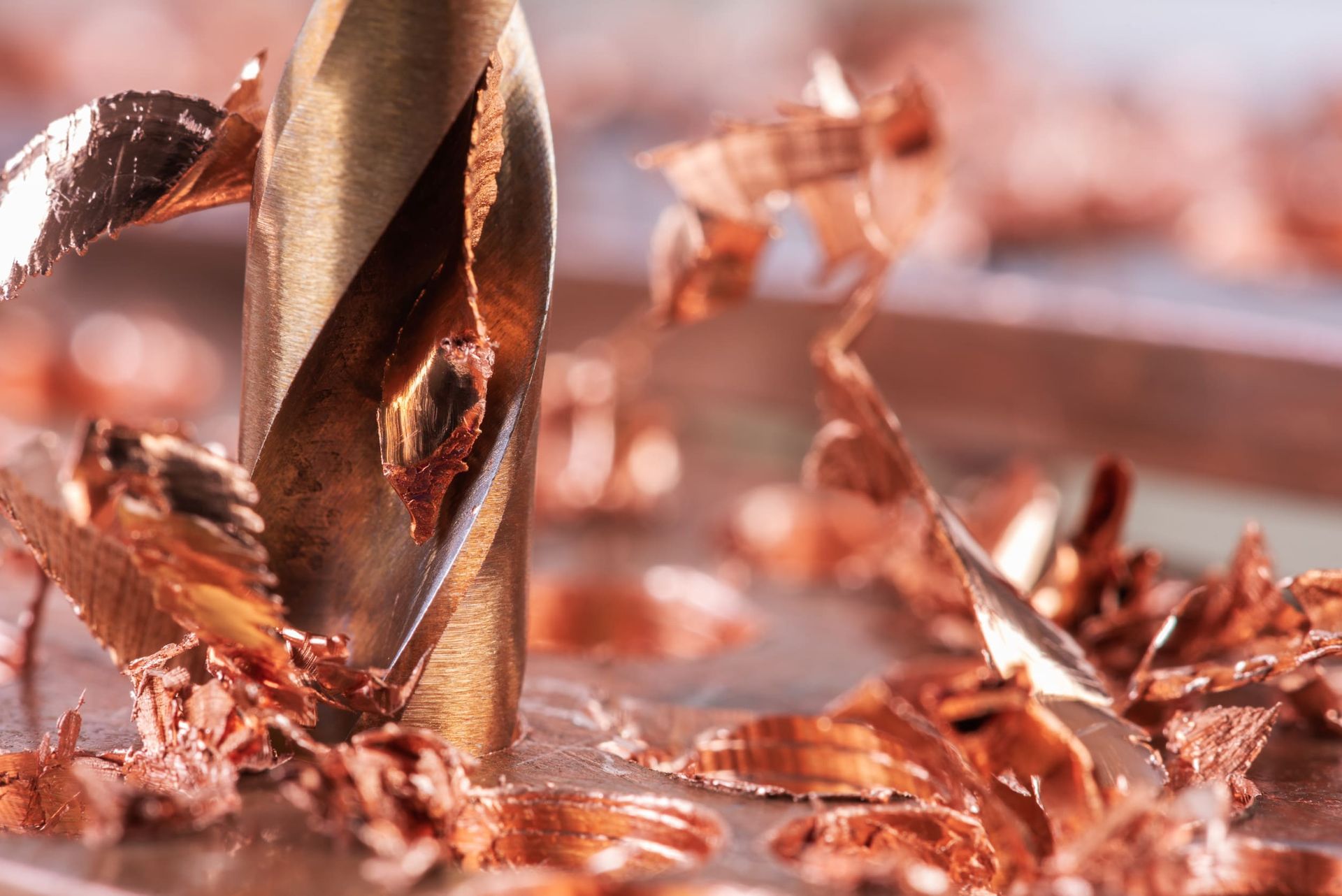 Un primer plano de una broca cortando un trozo de metal.