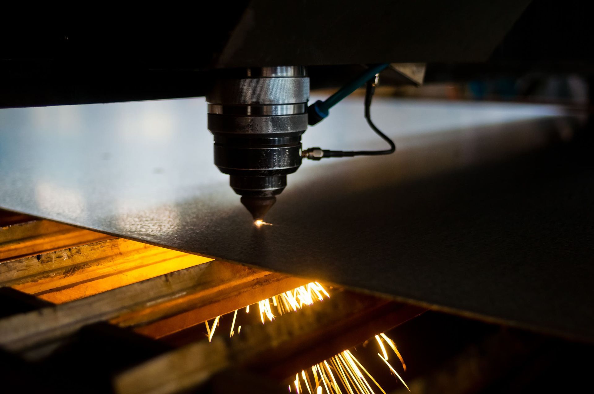 Una máquina está cortando un trozo de metal del que salen muchas chispas.