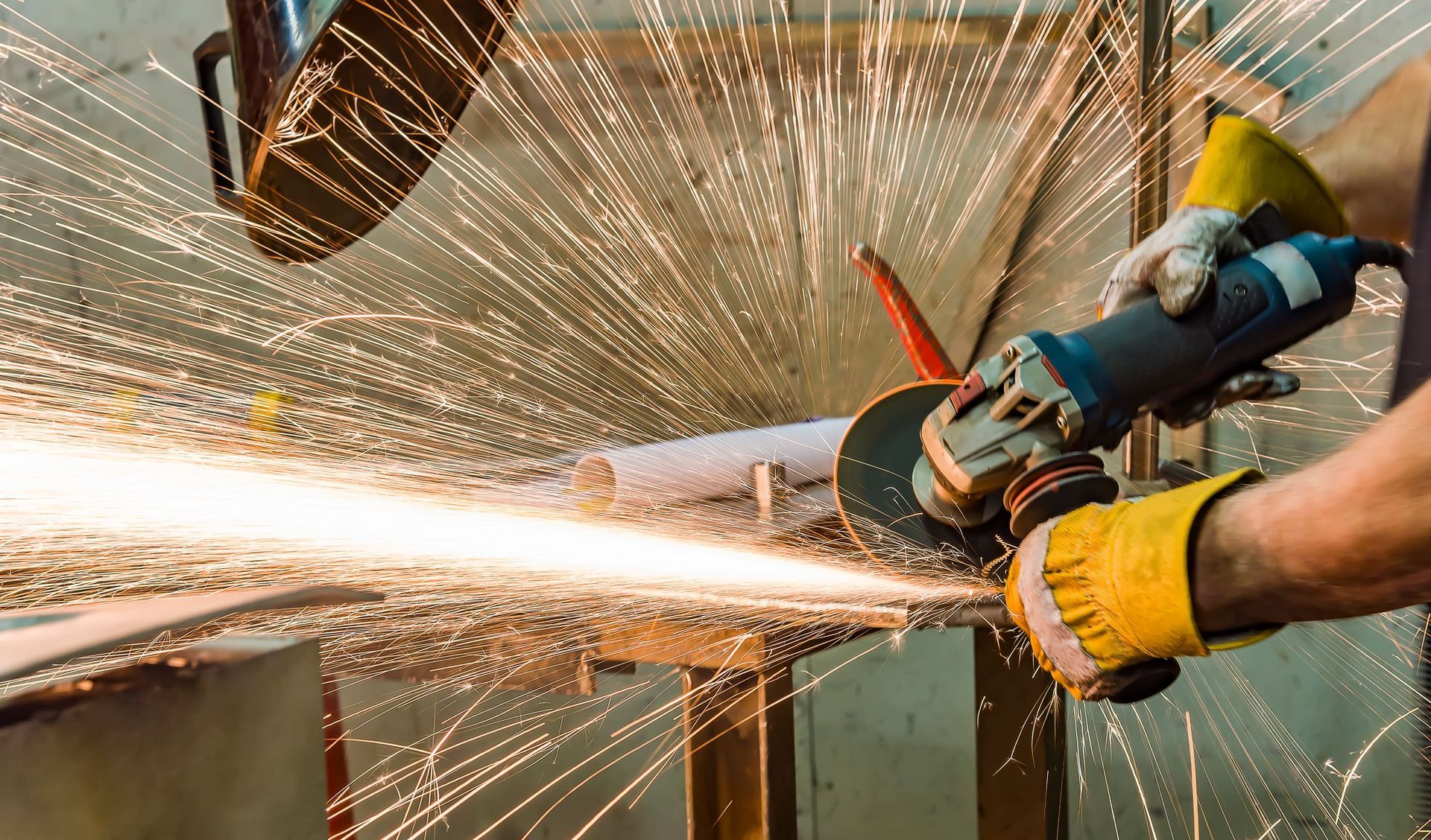 Un hombre está usando una amoladora para cortar un trozo de metal.