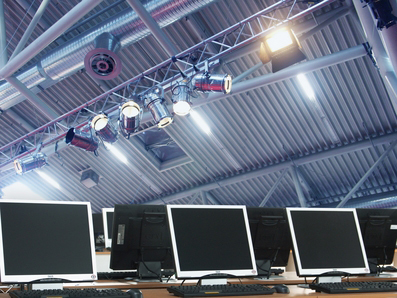 Una fila de monitores de computadora bajo un techo con luces.