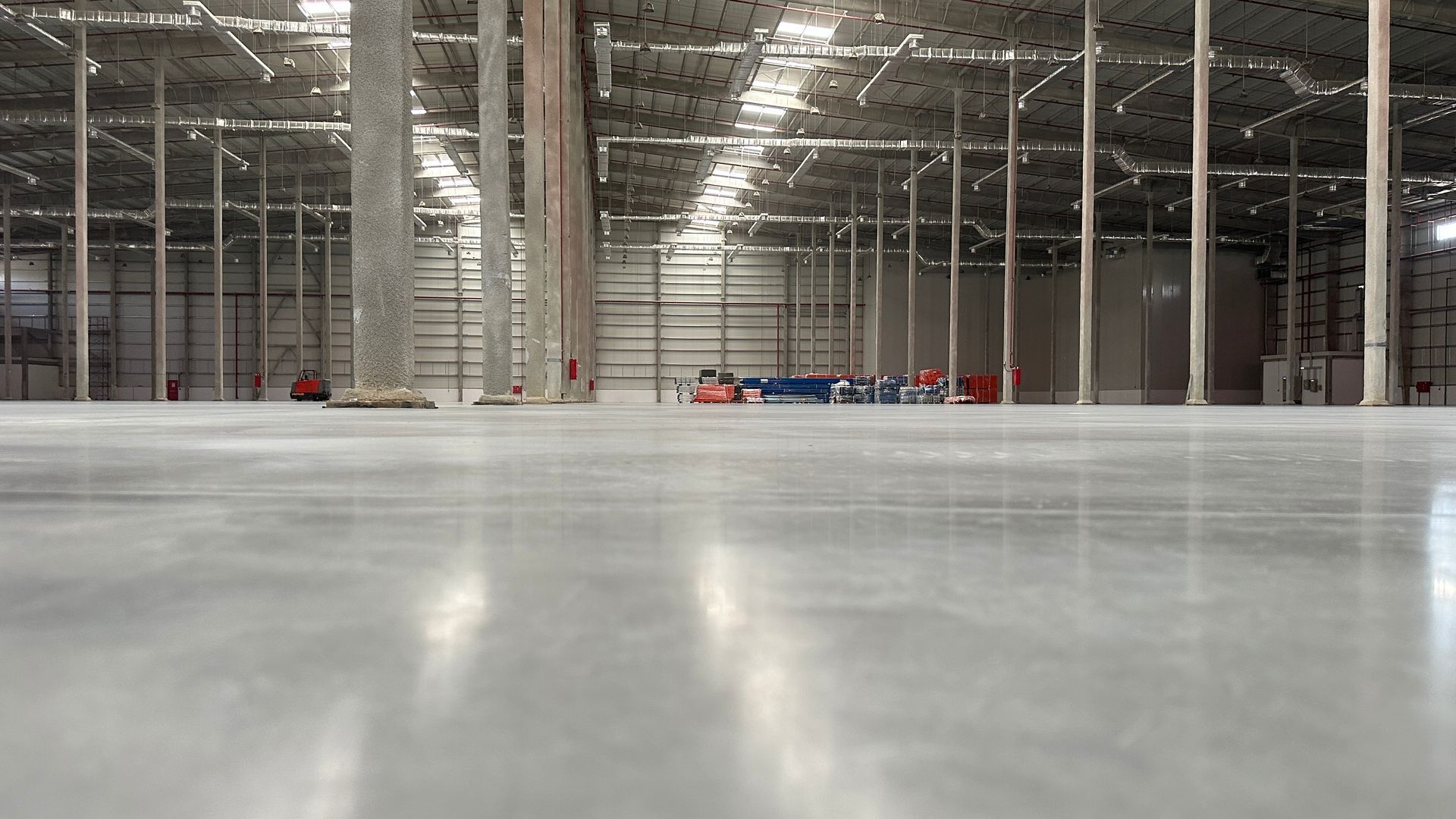 Alakuva valtavasta, tyhjästä varastosta, jossa on sileä betonilattia ja korkeat katot useiden pilarien varassa.