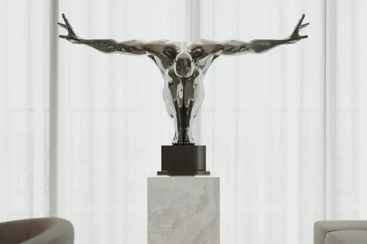Una escultura pulida de tono plateado que representa una figura con los brazos extendidos