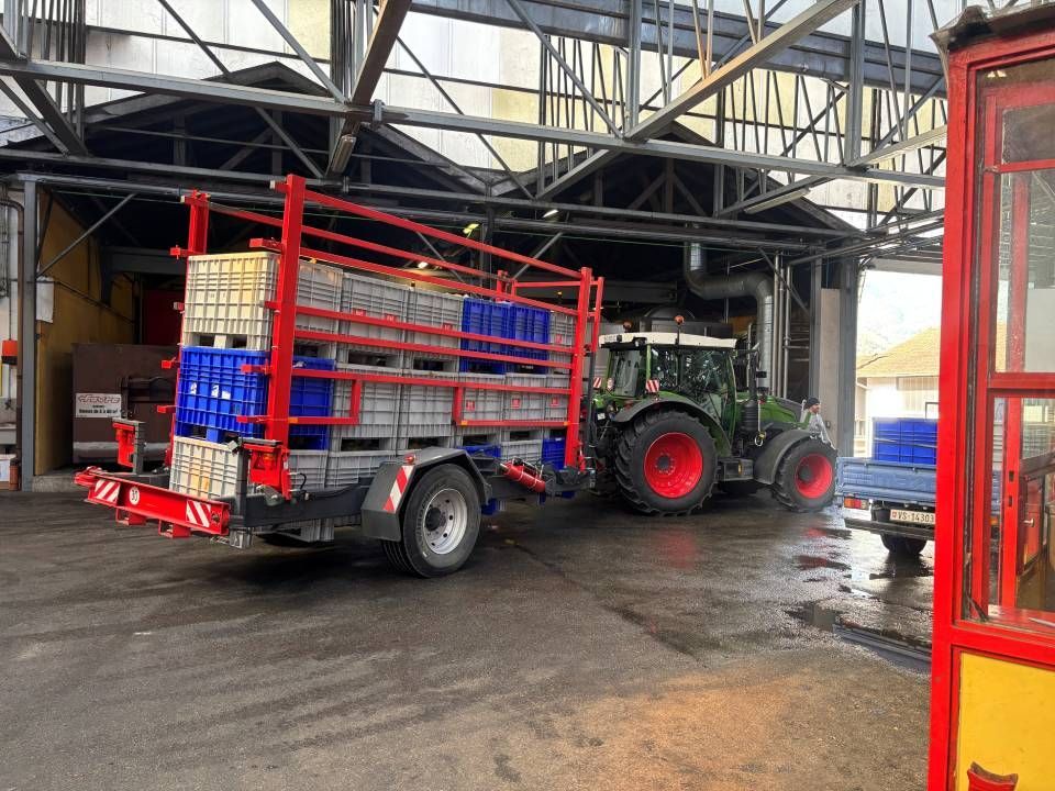 Un tracteur tirant une remorque chargée de conteneurs bleus à l'intérieur d'un entrepôt.