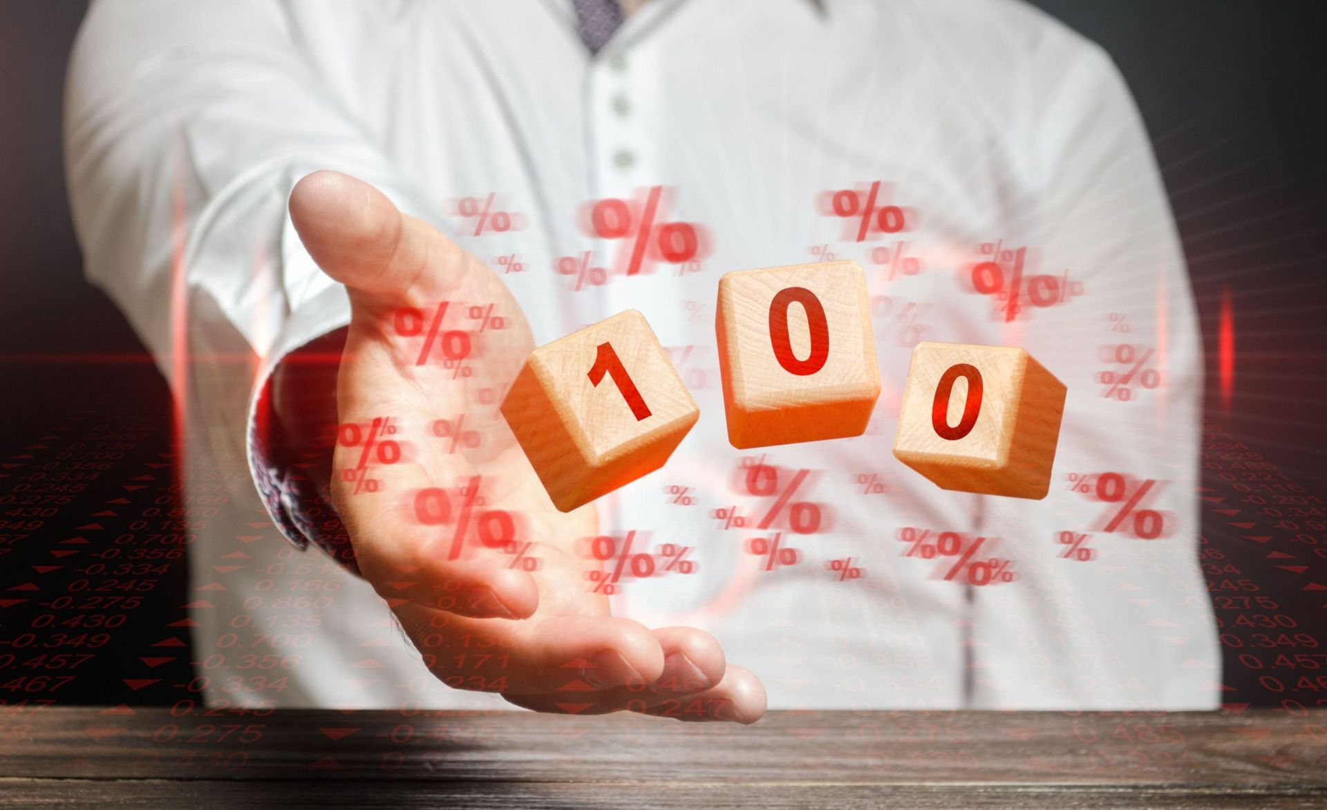 Un hombre sostiene un bloque de madera con el número 100 en él.