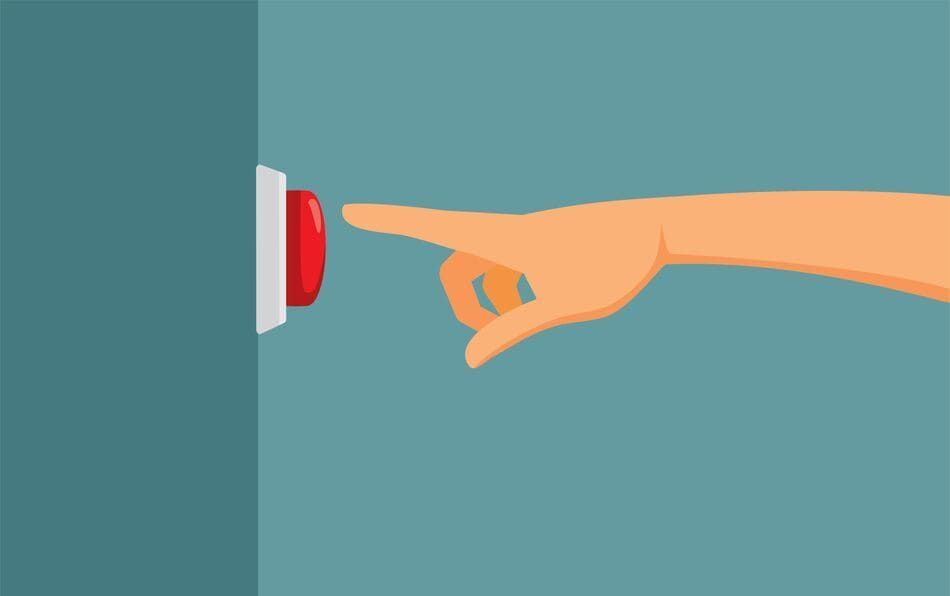 Una mano apunta a un botón rojo en una pared.