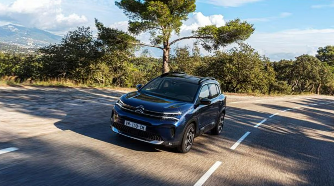 SUV Citroën bleu garé sur une route sinueuse avec un arrière-plan de montagne.
