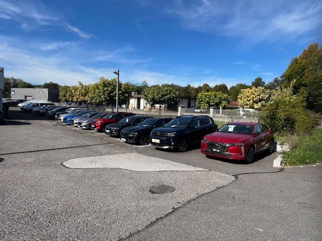 Un break Subaru blanc circulant sur une route, avec des montagnes en arrière-plan sous un ciel clair.