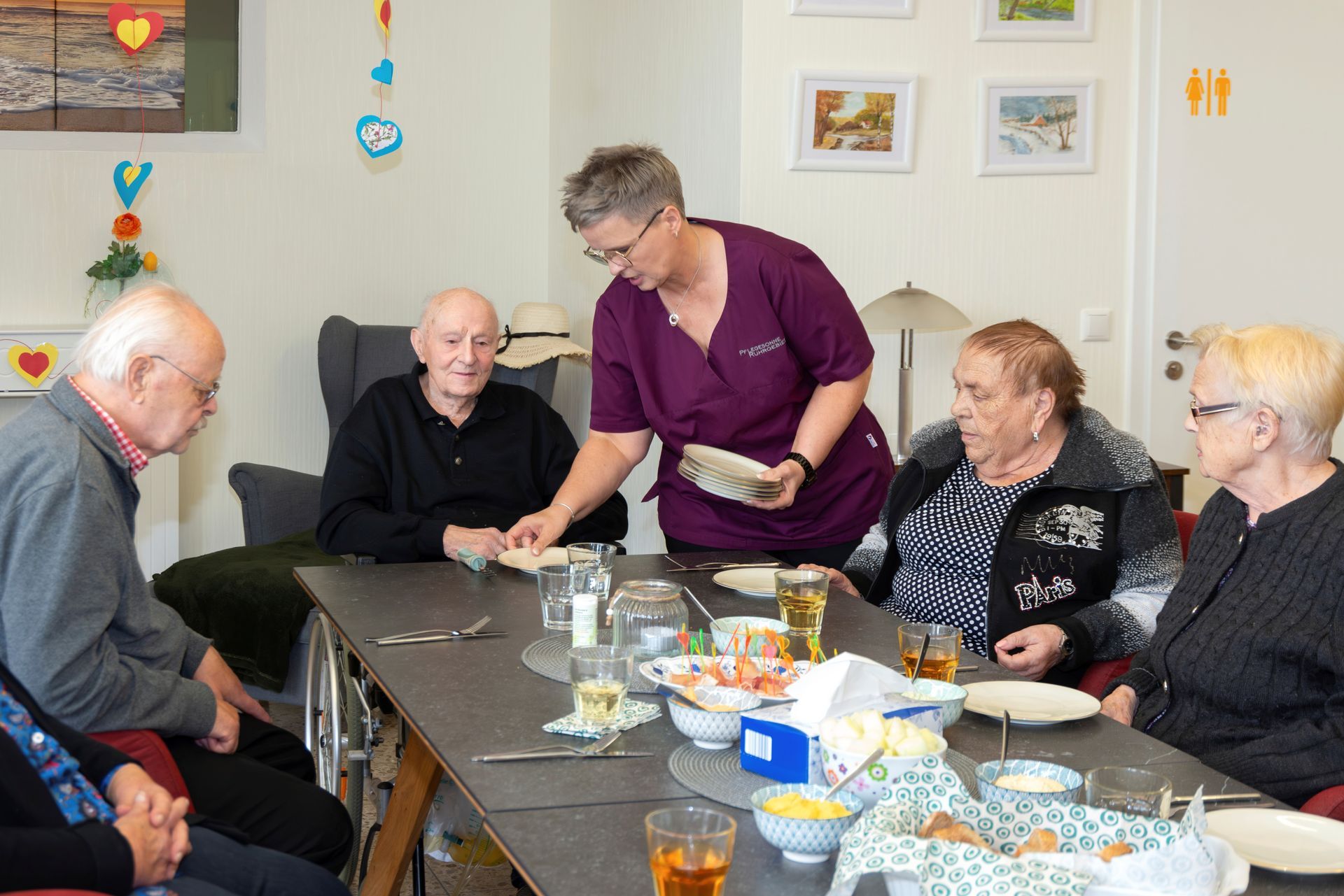 Pflegeanestelltedeckt Kaffeetisch mit umsitzeden Senioren