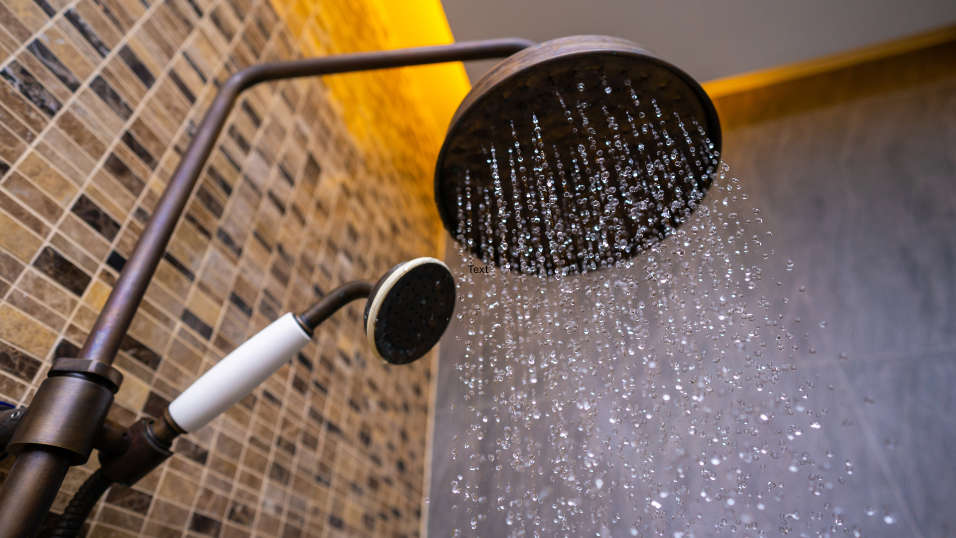 Showerhead spraying water in a tiled bathroom with gray and brown walls